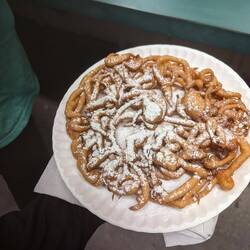 Deep fried funnel cakes covered in powdered sugar.