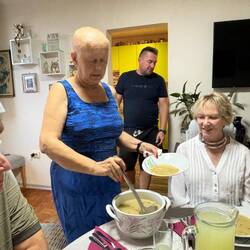 The mother in law serves chicken soup. Her son in the background