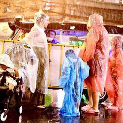 Sobald es anfängt zu regnen, starten die Regenbekleidungs-Verkäuferinnen erfolgreich ihr Business.