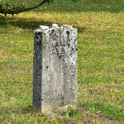 Never Forget, pebbles and stones of remembrance on top of a grave marker.