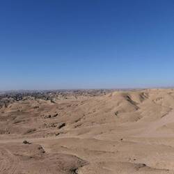 Rechts eintönige beige Flächen, links zerklüftete Mondlandschaft.