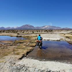 Flussüberquerungen gab es heute auch. Im Hintergrund der rauchende Vulkan Isluga