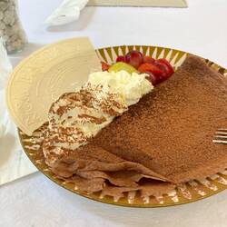 Chocolate crepe with a heap of whipped cream and fruit. Yummy