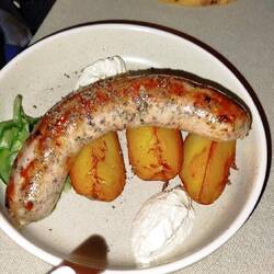 Spezialitäten Brotwurst Schwein mit Kartoffeln und Gurkensalat, dazu Schmand