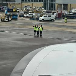 These 3 guys standing on the tarmac waving goodbye to the aircraft. JAL Service
