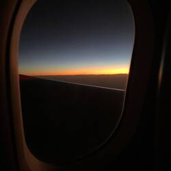 Sonnenaufgang aus dem Flugzeug, in der Ferne sehen wir schon die Bergspitzen