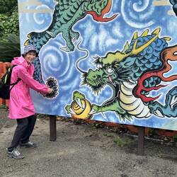 Lee holding the dragons tail on sign.