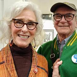 Pam and her boyfriend; explaining their badges are pro-Kamala, not for 'oo, la la' (with earrings)