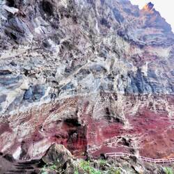 An der farbigen Felswand führt der Weg entlang.