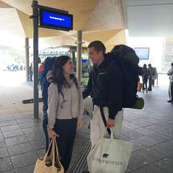 Mit Rucksack und Tasche warten wir auf den Bus, der leider Verspätung hat