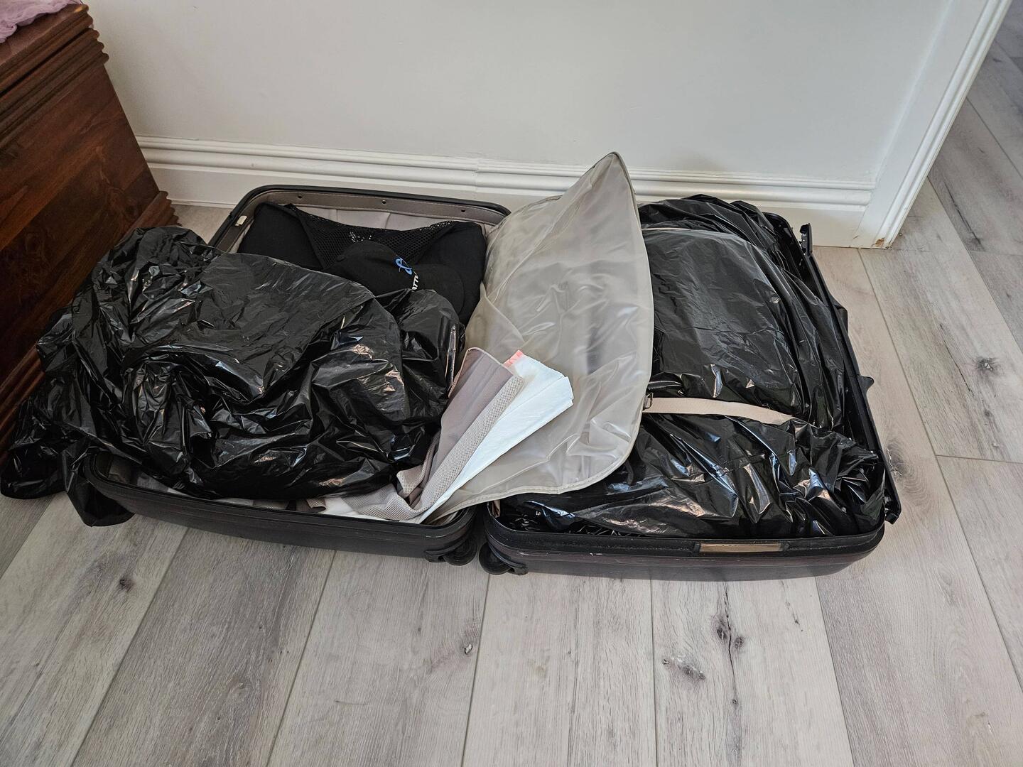One of several suitcases. Trash bags to guard against rain in case they get left out somewhere.