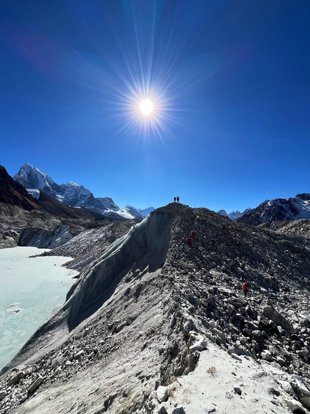 Geröll über einer dicken Eisschicht, darüber stehen wir in der Sonne.