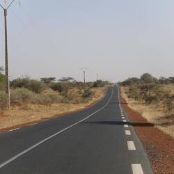 Bergauf, bergab über kleine Hügel führt die Straße durch die Savanne