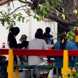 am Straßenrand brutzeln sich Einheimische ein Essen und sitzen plaudernd zusammen