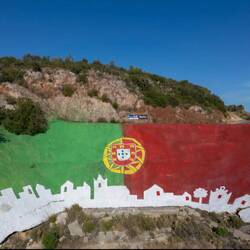 Eine riesige Flagge gemalt im Berg von an Seilen gesicherten Einwohnern