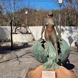 Skulptur einer nackten Frau in Benafim mit dem Dorfbrunnen im Hintergrund