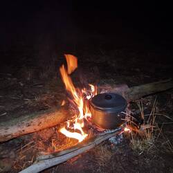 Das Abendessen kocht über dem wärmenden Feuer