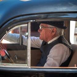 An elderly man in an elderly car