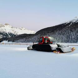 Der zugefrorene See wird mit Pistenfahrzeugen präpariert.