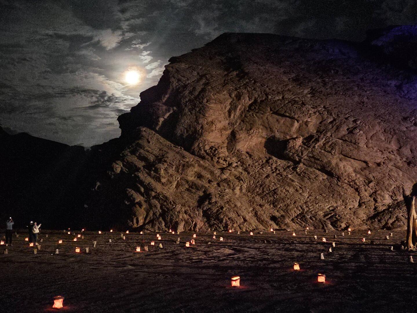Moonrise over the canyon, with luminarias in the foreground.