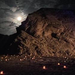 Moonrise over the canyon, with luminarias in the foreground.