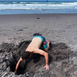 Vincent beim Versuch, heißes Wasser am hot water beach zu erbuddeln