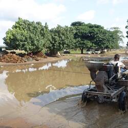 Ein halber See im Dorf - der stört den Motorradfahrer mit dem Maniokhäcksler nicht