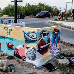 A graffiti artist and his work. A group of young athletes on the right of the image.