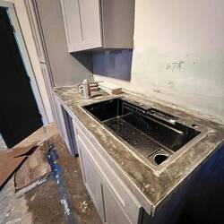 Kitchen sink is made flush with the concrete countertop