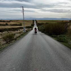 Links und rechts Felder. Im Hintergrund die schneebedeckten Gipfel der Sierra Nevada