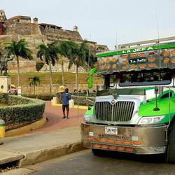 A Chiva bus with the San Felipe de Barajas Fort in the background.