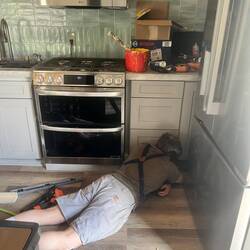 Brice getting the cabinet trim installed and caulked.