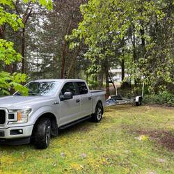Truck and trailer parked amongst the trees.