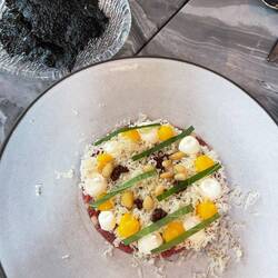 Beef tartare with crème fraiche, egg yolk dollop, mustard seeds and toasted seaweed chips