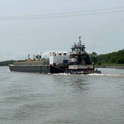 This is known on the waterways as a 'tow'. But the tug pushes the load rather than towing it.