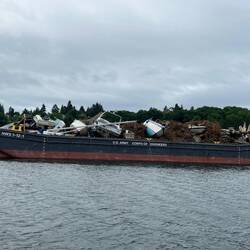 US ACE barge has a number of damaged sail and power boats on it.