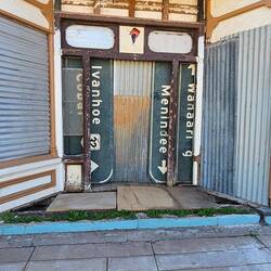 Boarded entry to a derelict shop using local street signs.