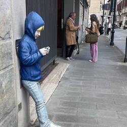 The boy is a statue but the people behind him are real