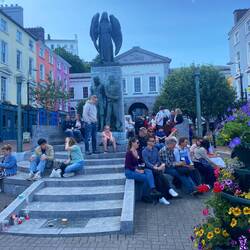 Everyone drinking their Guinness in the town square watching a band