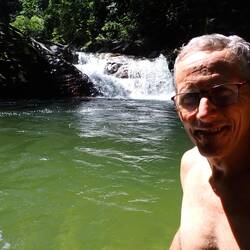 A fleshing swim in a pond beneath a scenic waterfall.