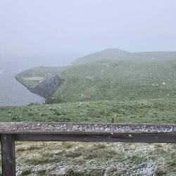 There are sheep on the hillside, but the snow squall blocked them.