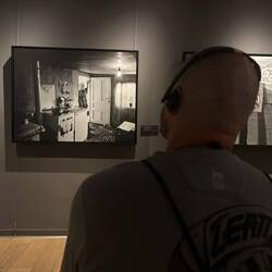 Toto betrachtet das Foto von einer Frau, die auf ihre Söhne wartet