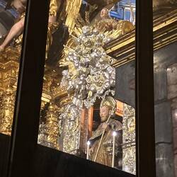 People hug him as they walk behind him at the high alter