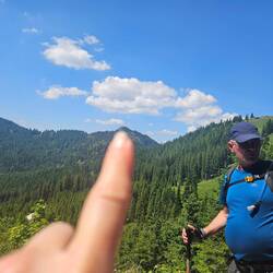 Abstieg. Rechts hinter Papa die Alm. Der Finger zeigt das Gipfelkreuz vom Schildenstein