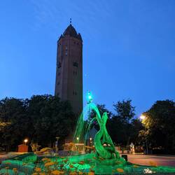 Wasserturm als höchstes Gebäude der Stadt und kleinem Park mit wasserspuckender Schlange🪱