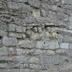 The stone with sculpted heads has been reused from elsewhere in the Roman city