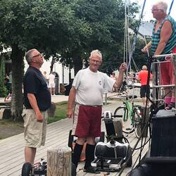 Ein Elektrorollstuhl wird in Teilen gemeinsam mit Flaschenzug von einem Boot gehoben.