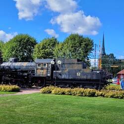 Historische Dampflok neben der noch aktiven Bahnstrecke