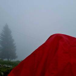 Nein, kein Zelt! Andreas unter seinem Regenumhang beim "Mittagspfüsi", trotz Nebel!😉