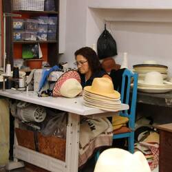 Eine Hutmacherin näht das Zierband präzise in den fertigen Toquilla-Hut ein.